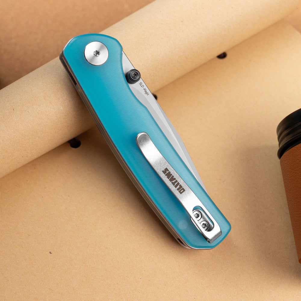 Closed OLITANS Gecko SE G080 Blue Acrylic knife on a tan display surface