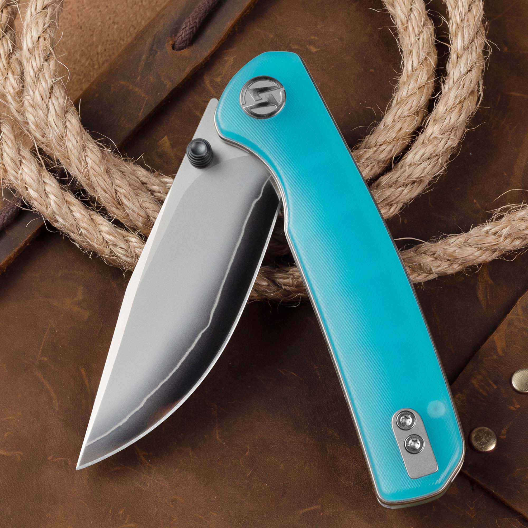 Open OLITANS Gecko SE G080 Blue Acrylic knife displayed with rope and wood